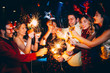 © Astarot - Group of friends having fun and holding sparklers at New Year's party