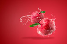 Water Splashing On Fresh Red Apple On Red Background.