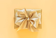 Festive Background With Gold Gift, Gift Box With Ribbon And Bow On Gold Background, Flat Lay, Top View