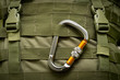 aluminum climbing carabiner attached to a green military tactical backpack