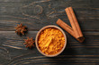© Atlas - Wood bowl with turmeric and cinnamon on wooden background, top view