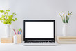 Office workspace with laptop mockup, books, white daffodils in a vase, office supplies on a light background