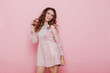 Portrait of a beautiful fashionable woman with haircurls in a pink holiday dress