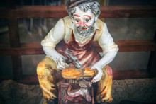 Shoemaker statue. Funny statuette of an ancient profession: craftsman mends a shoe
