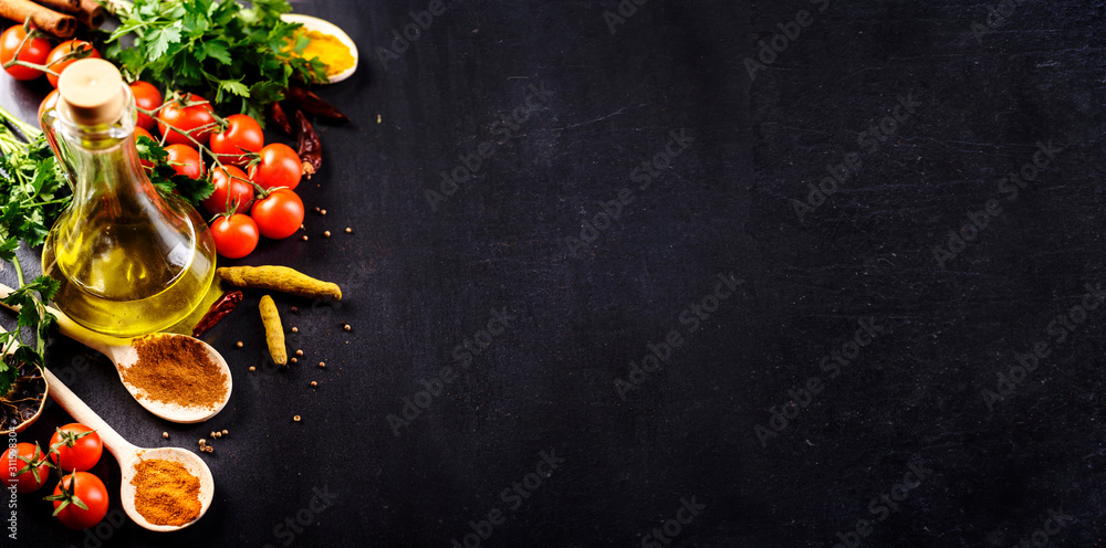 Food background. Top view of olive oil, cherry tomato, herbs and spices on rustic black slate. Colorful food ingredients border. - obrazy, fototapety, plakaty 