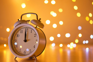 Wall Mural - White alarm clock show 12.00 at night with light bokeh background, midnight before new year.