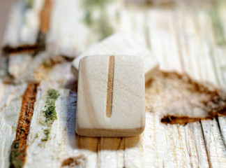 Wooden rune Isa close-up on a wooden background. Soft focus