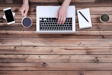 Poster - Female hands typing on laptop keyboard with smartphone, notepad and cup of coffee