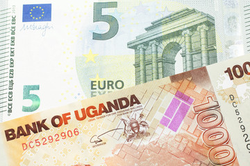 A five euro European bank note with a one thousand Ugandan shilling bill close up in macro