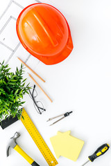 Builder work desk with hard hat, instruments and blueprints on white background top-down frame copy space