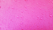 Water Drops Background On The Pink Glossy Surface, Rain Droplets On Pink Texture For Cosmetics, Drink Product.