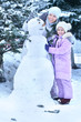 © aletia2011 - Portrait of happy mother and daughter making snowman , posing outdoors in winter