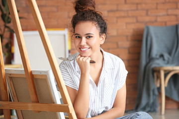 Beautiful female African-American artist painting in studio