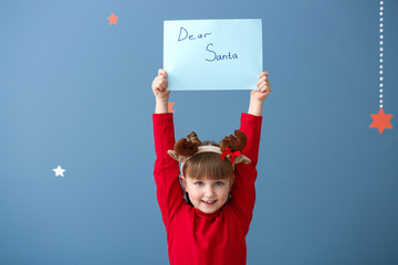 Wall Mural - Cute little girl with letter to Santa Claus on color background