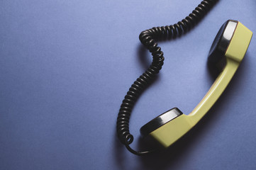 Vintage green telephone handset. phone receiver isolated on blue background. old communication technology