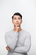 © makistock - A portrait of a young asian man thinking looking up isolated over white background