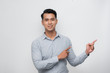 © makistock - Young asian man smiling and looking at the camera pointing with two hands and fingers to the side