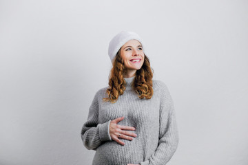 Happy pregnant young woman in Santa hat looking dreamily.