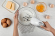 Woman whipping egg whites at wooden table, top view. Baking pie