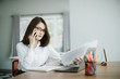 © uinmine - Beautiful young woman working on her laptop and talking phone in her office.