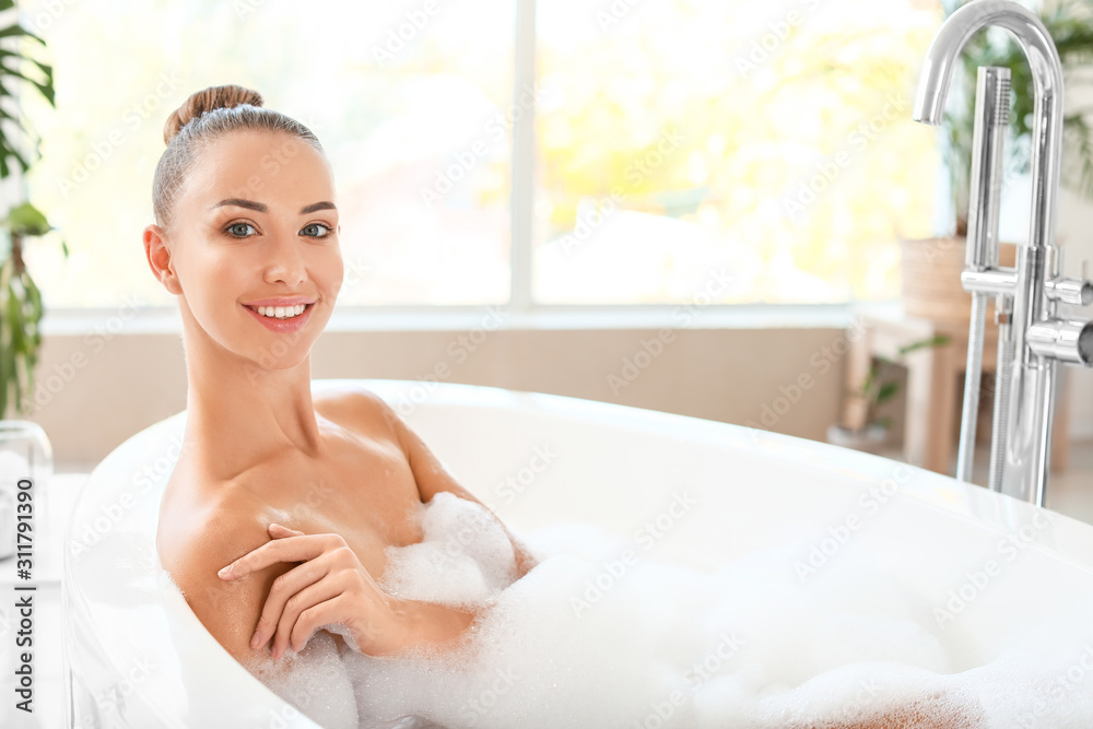 Beautiful young woman relaxing in bathtub