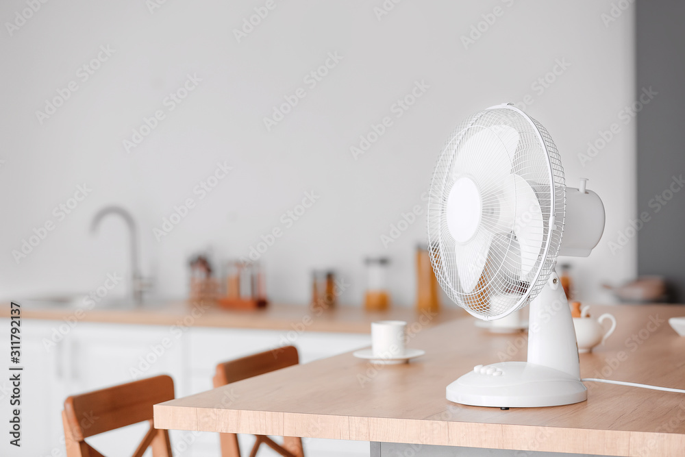 Electric fan on table in kitchen - obrazy, fototapety, plakaty 