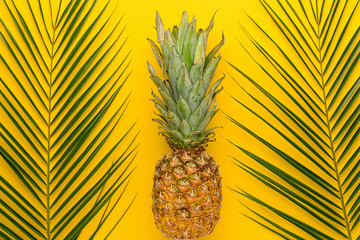 Fresh ripe pineapple and tropical leaves on color background