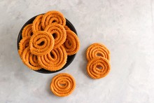 Crunchy Fried Homemade Chakli In A Bowl With Sesame Seeds. Chakli Is A Savory Snack From India Made Out Of Rice, Mixed Yellow And Green Lentils Along With Spices. Mostly Eaten During Diwali Festival