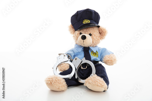 Fotografía Cute teddy in policeman uniform and handcuffs isolated against white background