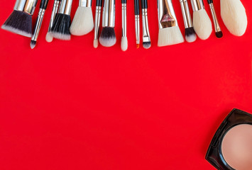 Set of brushes for makeup and powder on a red background. Flat lay, copy space, top view.