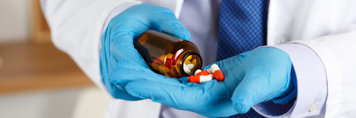 Wall Mural - Male medicine doctor hands in blue gloves holding and offering pile of pills