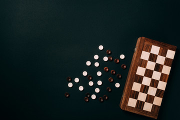 Wall Mural - Top view of white and brown checkers with chessboard isolated on black