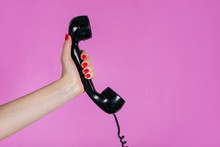 Female Hand Holding Old And Retro Telephone Headset Isolated On Pink Background In Studio. Girl Hands With Red Manicure On Fingers. Minimalism And Retro Concept