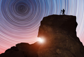 Wall Mural - beautiful starry night landscape. a silhouette of a photographer stands on a rock and looks at a bea