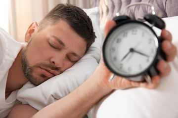 Wall Mural - Man with alarm clock sleeping at home in morning