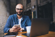 © GalakticDreamer - Content modern man in glasses texting on smartphone while resting at street cafe