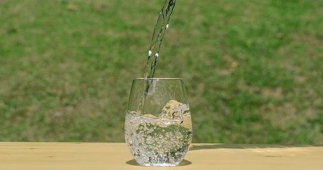 Wall Mural - Human hand pick up the bottle and pouring pure water in to the glass make the spread of water crystal bubble