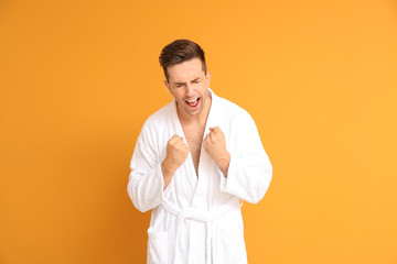 Wall Mural - Happy man in bathrobe on color background