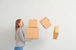 © Pixel-Shot - Bothered woman dropping cardboard boxes on light background