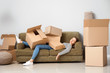 © Pixel-Shot - Sleeping woman with heap of moving boxes lying on sofa in new house