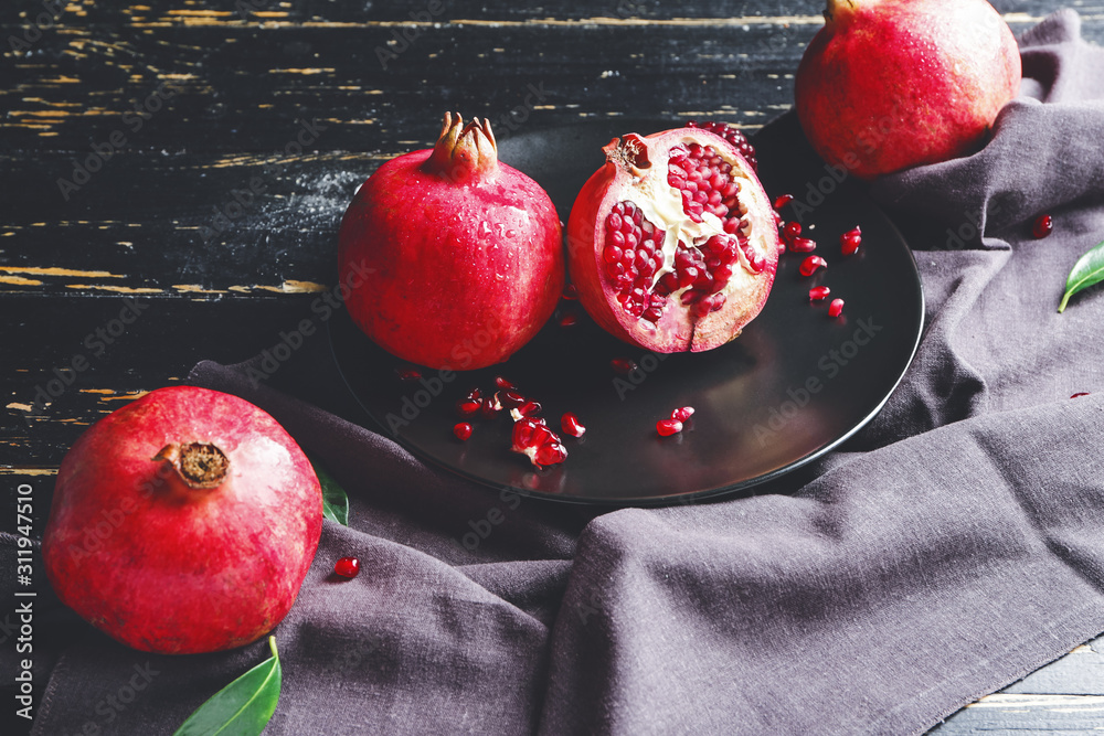 Plate with tasty pomegranate on dark table