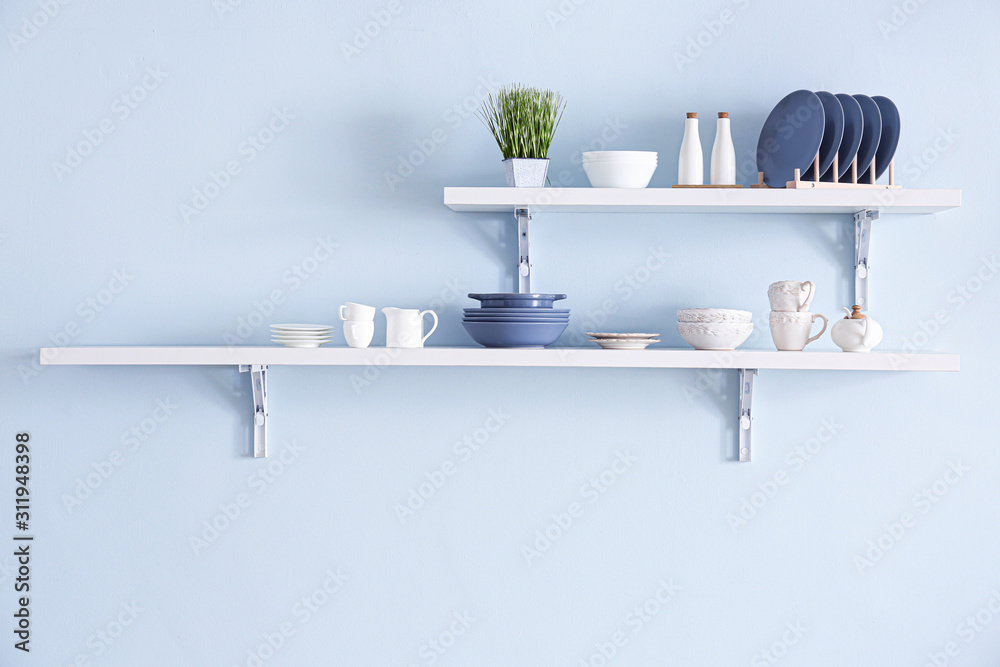 Shelves with tableware hanging on color wall