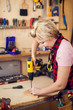 © Aleksej - Young handy woman with short blond hair working with screwdriver.