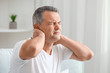 © Pixel-Shot - Mature man suffering from neck pain at home