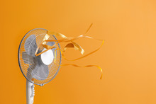 Electric Fan With Fluttering Ribbons On Color Background