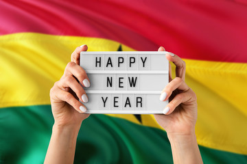 Ghana New Year concept. Woman holding Happy New Year sign with hands on national flag background. Celebration theme.