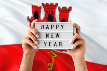 Gibraltar New Year concept. Woman holding Happy New Year sign with hands on national flag background. Celebration theme.