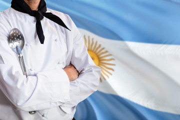 Argentina domestic food concept. Professional chef in white uniform is standing with metal spatula. Copy space for text.