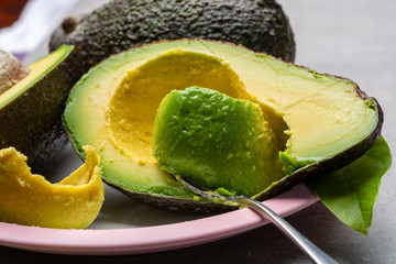 Eating of fresh ripe green organic hass avocado fruit with spoon