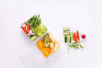 lunch box with a vegetarian set of fresh vegetables and fruits for a quick lunch on a white background Top view